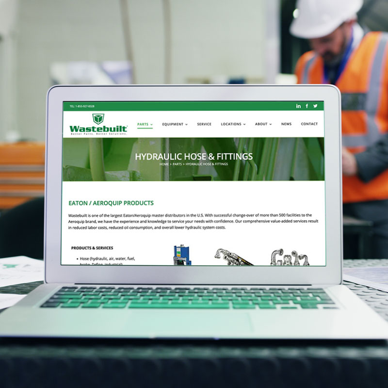 Wastebuilt.com shows Hydraulic Hoses and Fittings page on workers desk.
